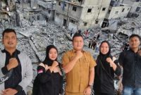 Kabag Kesra Pemkab Madina Bahruddin Juliadi foto bersama usai menerima donasi dari Ketua Karang Taruna dari Pantai Barat untuk rakyat Palestina dengan berlatar belakang sebuah pemandangan menunjukkan rumah-rumah dan bangunan yang hancur akibat serangan Israel di Kota Gaza, 10 Oktober 2023 yang diambil dari google/Reuters/Mohammed Salem.