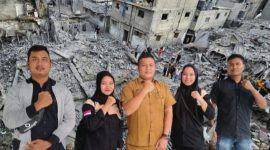 Kabag Kesra Pemkab Madina Bahruddin Juliadi foto bersama usai menerima donasi dari Ketua Karang Taruna dari Pantai Barat untuk rakyat Palestina dengan berlatar belakang sebuah pemandangan menunjukkan rumah-rumah dan bangunan yang hancur akibat serangan Israel di Kota Gaza, 10 Oktober 2023 yang diambil dari google/Reuters/Mohammed Salem.