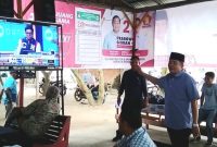 Ketua Tim Kampanye Daerah (TKD) Prabowo-Gibran Kabupaten Mandailing Natal (Madina), H. Erwin Efendi Lubis, SH mencermati hasil hitung sementara (quick qount) di televisi bersama pendukung, Panyabungan, Rabu (14/2/2024). [Foto: Joki Nasution].